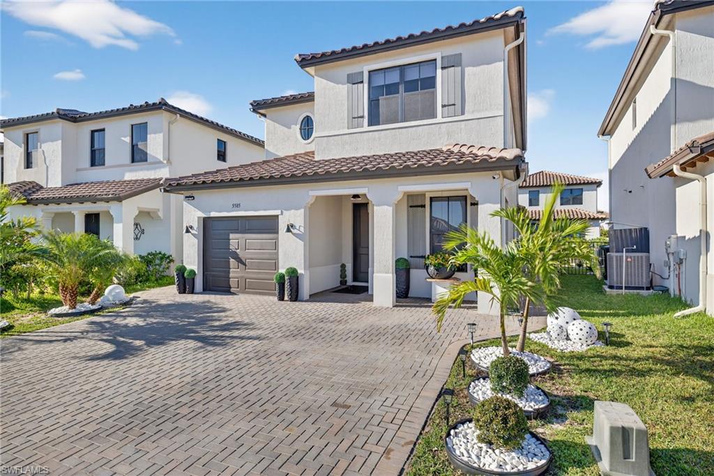 Mediterranean / spanish house featuring decorative driveway, stucco siding, a tiled roof, and a front lawn