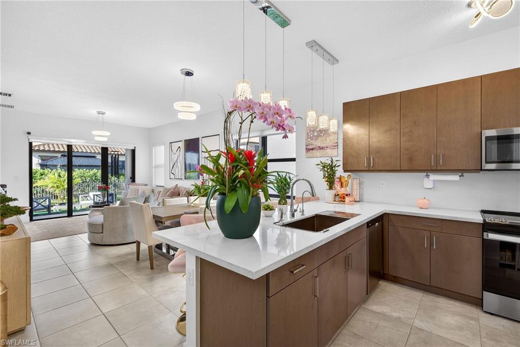 Kitchen with a peninsula, pendant lighting, stainless steel appliances, open floor plan, and light tile patterned flooring