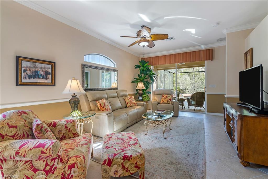 Living room with ceiling fan, ornamental molding, and light tile patterned flooring