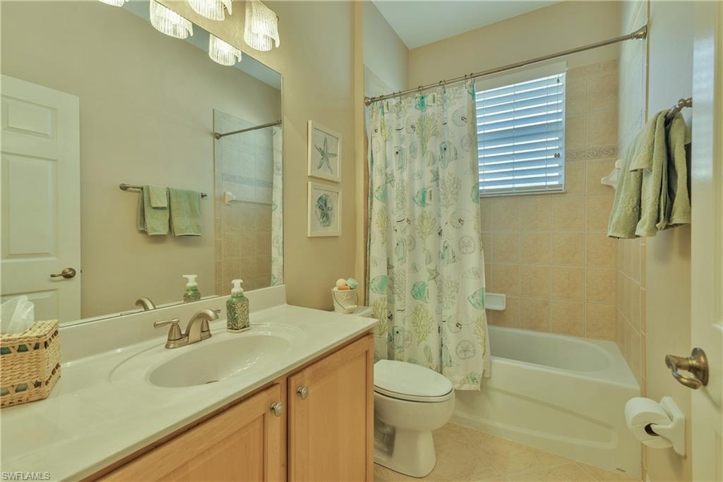Bathroom featuring vanity, shower / bath combination with curtain, and light tile patterned flooring