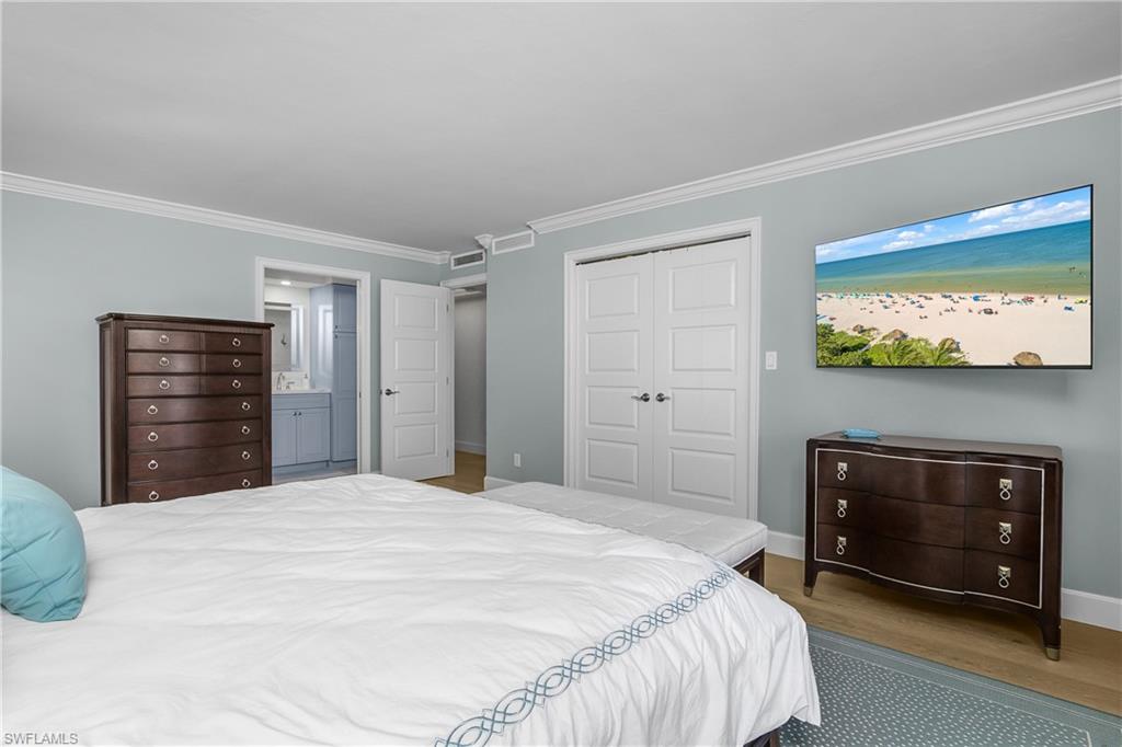 Bedroom with a closet, light wood flooring, crown molding, large walk in closet and connected bathroom
