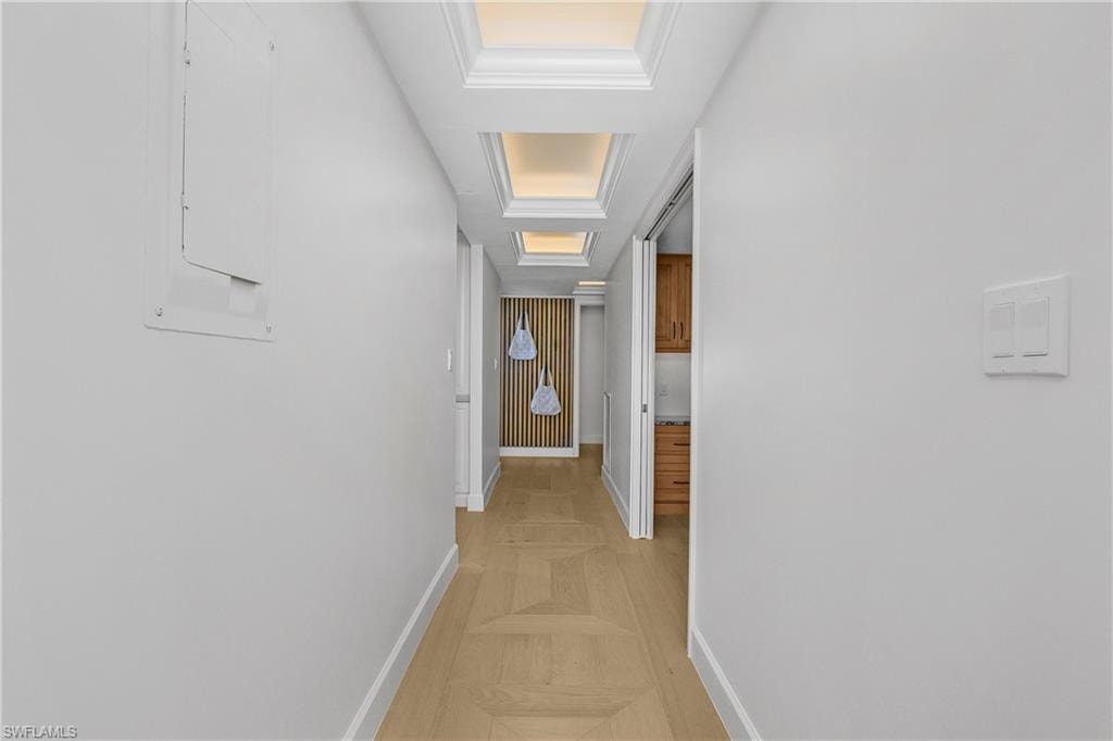 Hallway with beautiful custom floors, a lighted tray ceiling, and feature wall