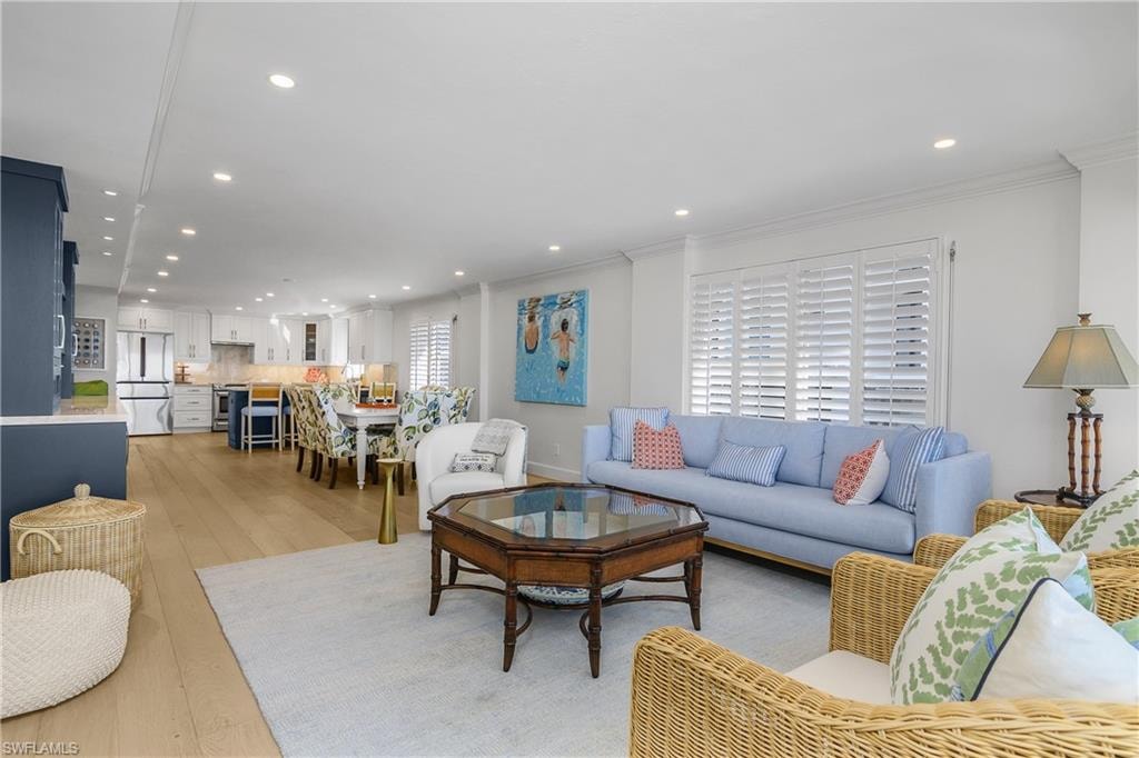Living area with light wood custom floors, recessed lighting, and crown molding