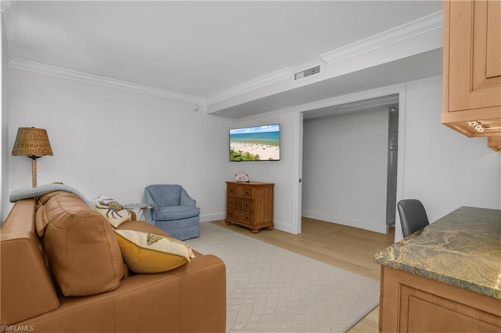 Living room featuring light wood-style flooring and ornamental molding