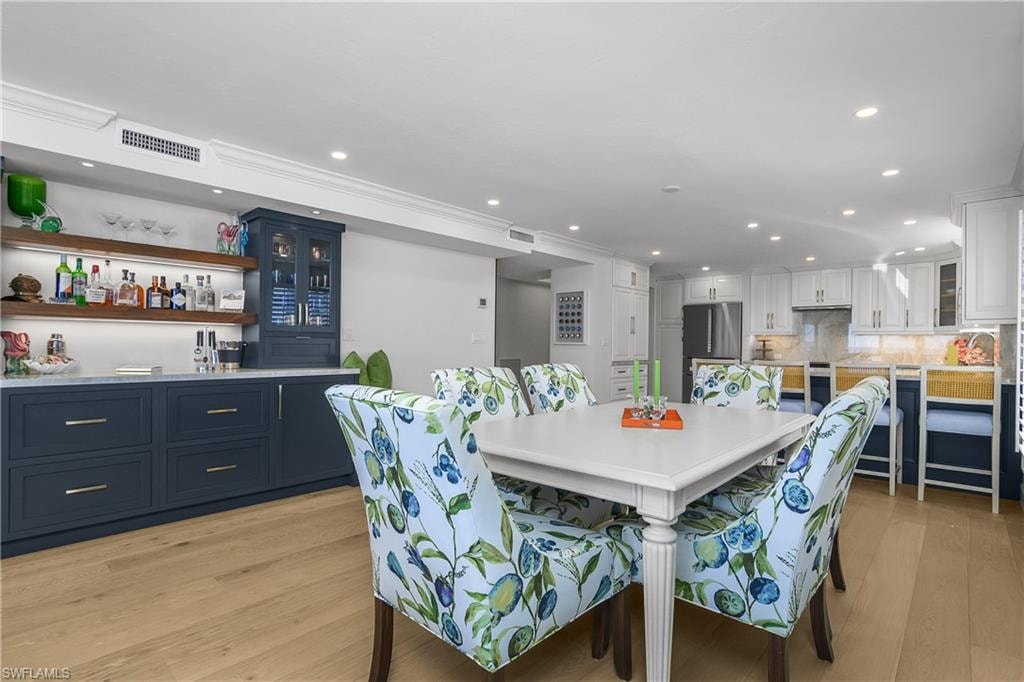 Dining space with light wood custom flooring, recessed lighting, and custom built in cabinetry with wine cooler