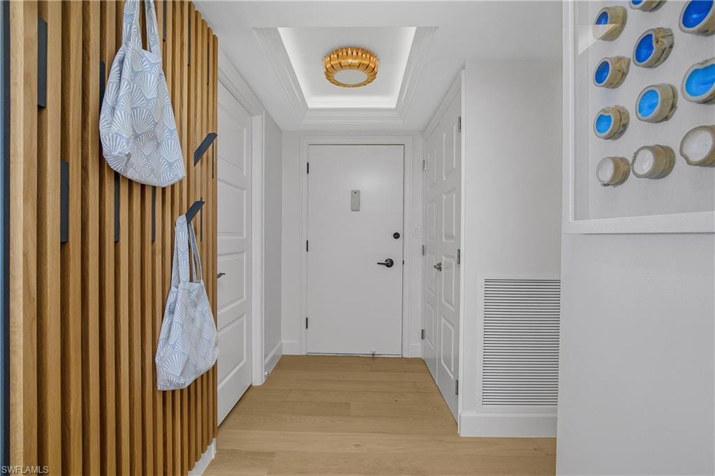 entry foyer with a raised ceiling, custom feature wall, and wood floors