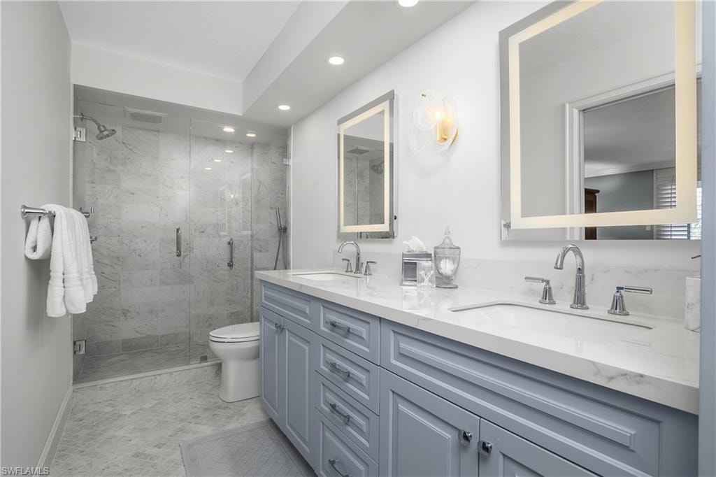 Main en suite, Full bath featuring double vanity, a marble finished shower, lighted vanity mirrors and recessed lighting