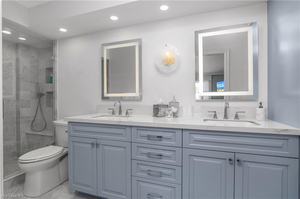 Full bathroom with double vanity, a marble finish shower, and recessed lighting