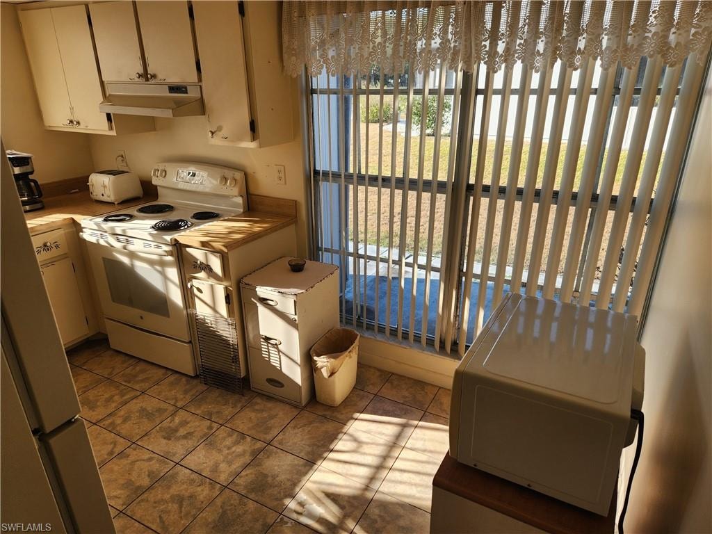 Kitchen with white appliances and dark tile patterned flooring
