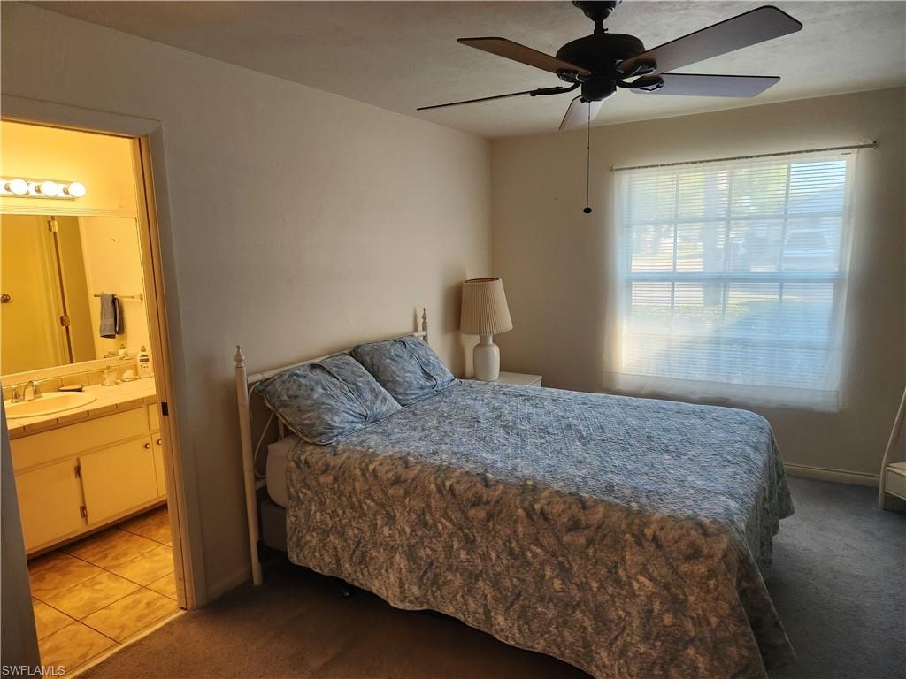 Carpeted bedroom with a sink and a ceiling fan