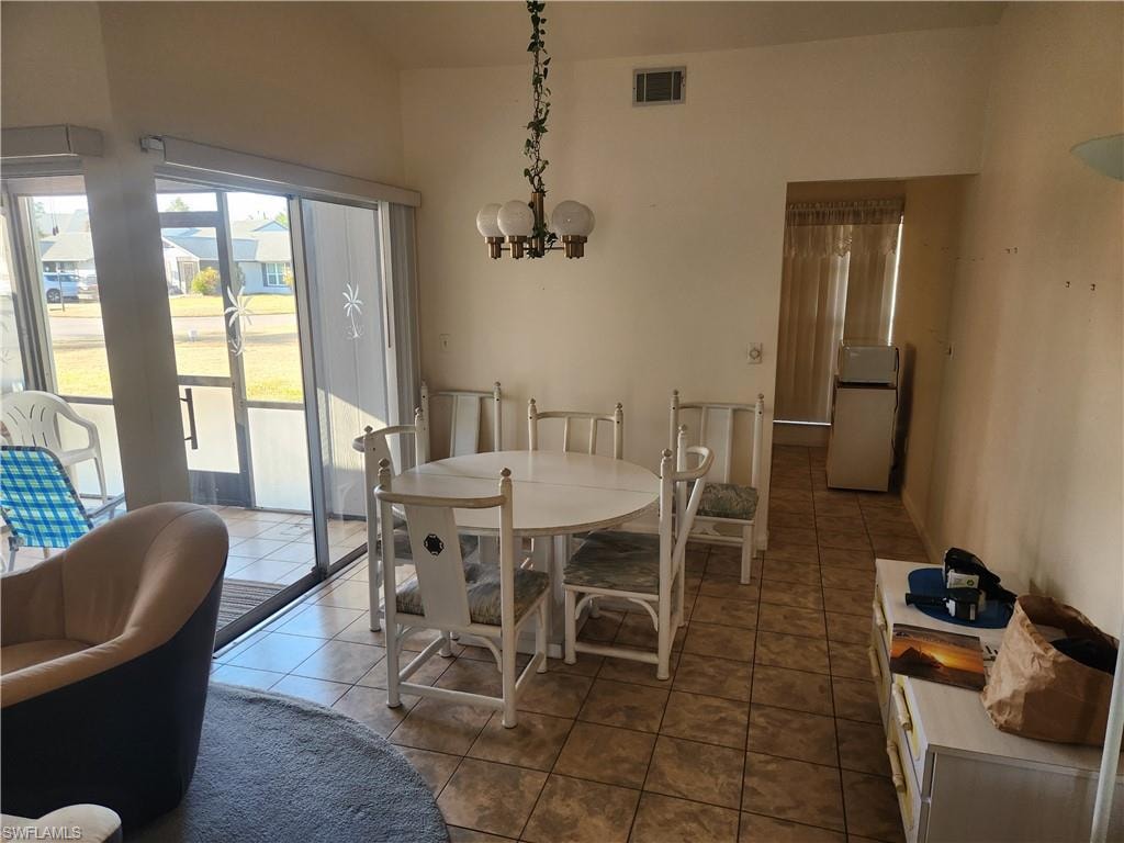 Dining area featuring dark tile patterned floors and a chandelier
