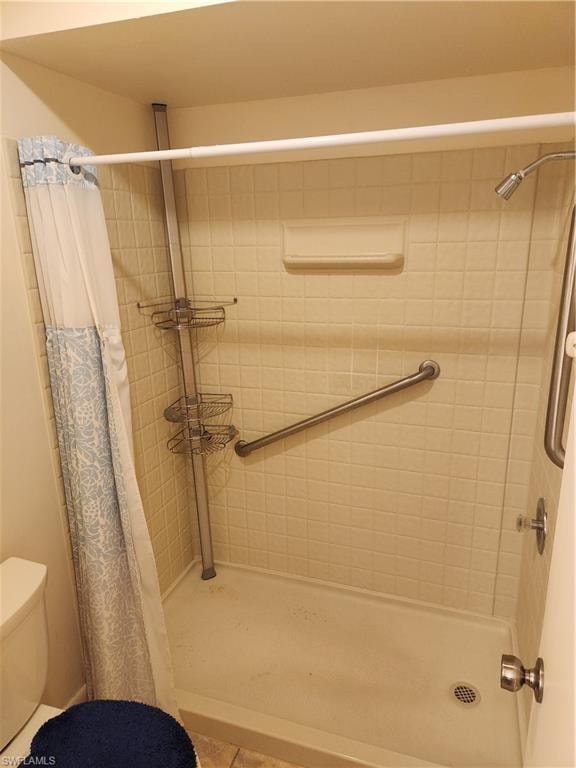 Full bath with tiled shower and toilet