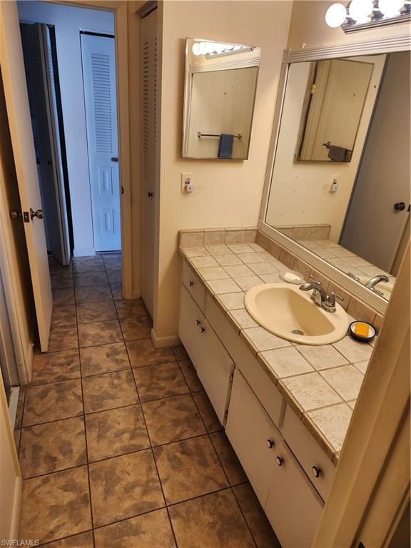 Bathroom featuring vanity, a closet, and dark tile patterned floors