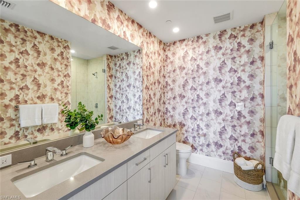 Ensuite guest bathroom with double sinks and a walk in shower.