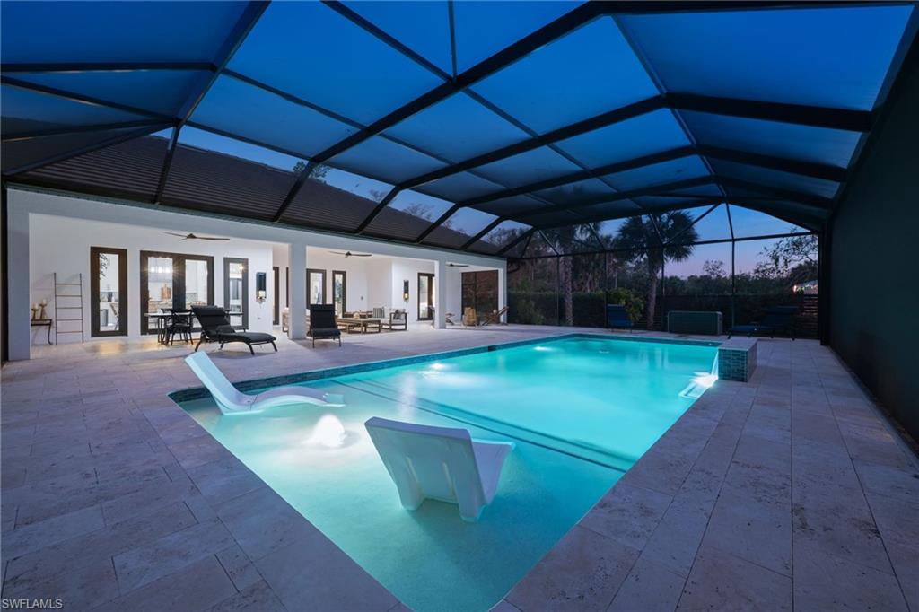 Pool at dusk featuring an outdoor pool, a sunroom, and a patio area