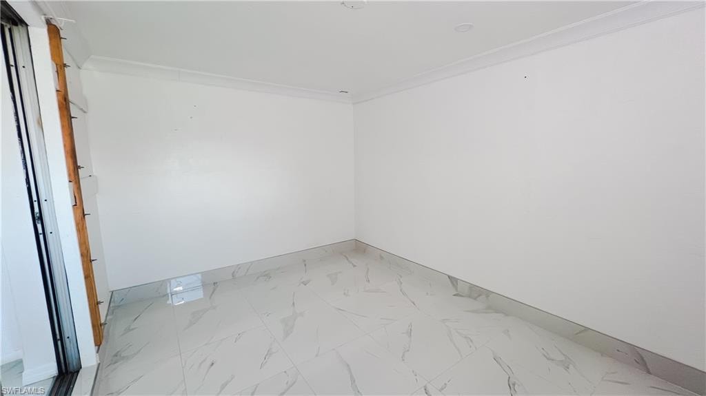 Empty room with light marble finish flooring and ornamental molding