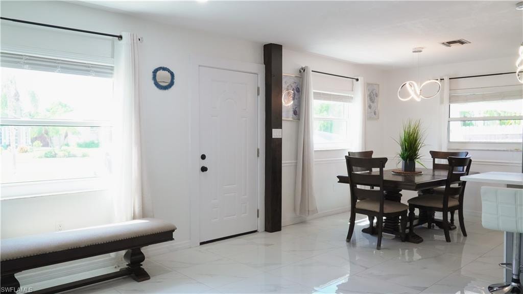 Dining room featuring plenty of natural light, light marble finish flooring, and suspended lighting