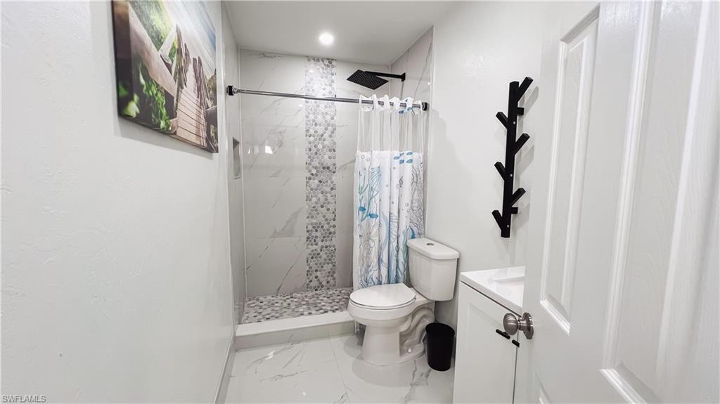 Bathroom with vanity, a stall shower, and light marble finish floors