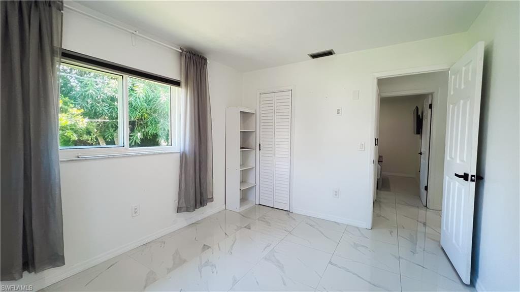 Unfurnished bedroom featuring light marble finish flooring and a closet