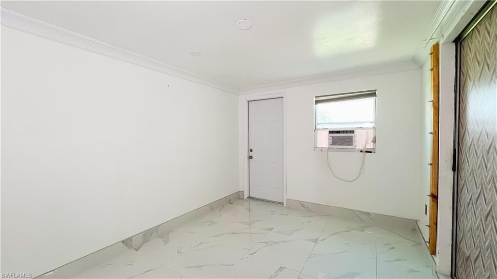Spare room with light marble finish floors, crown molding, and cooling unit