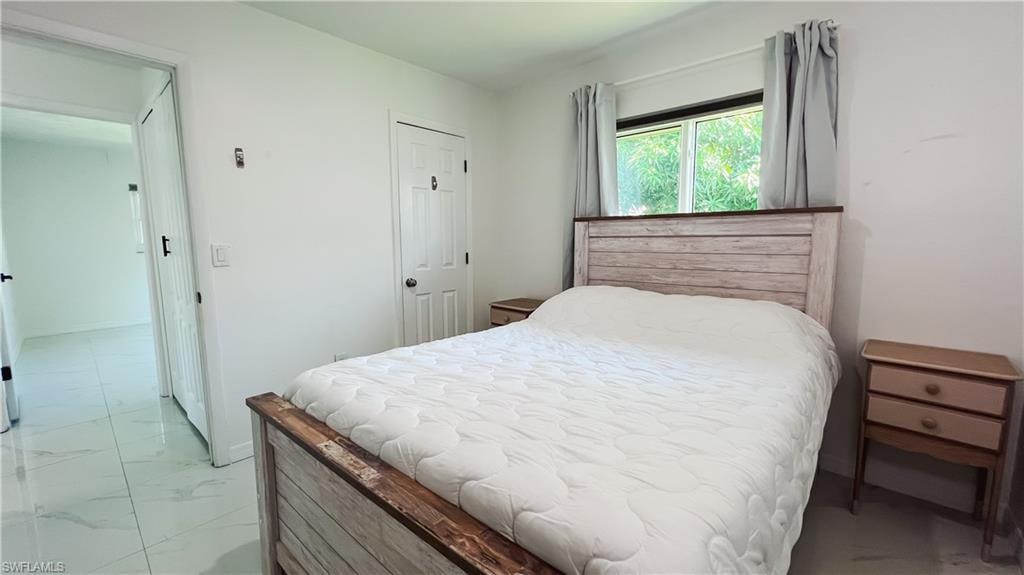 Bedroom with a closet and light marble finish floors