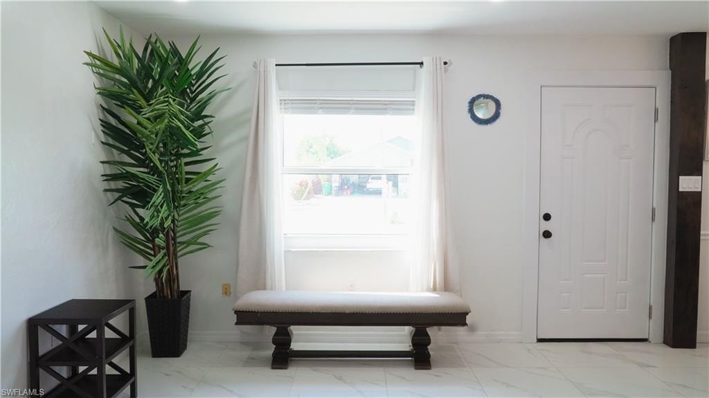 Entrance foyer with baseboards and light marble finish flooring
