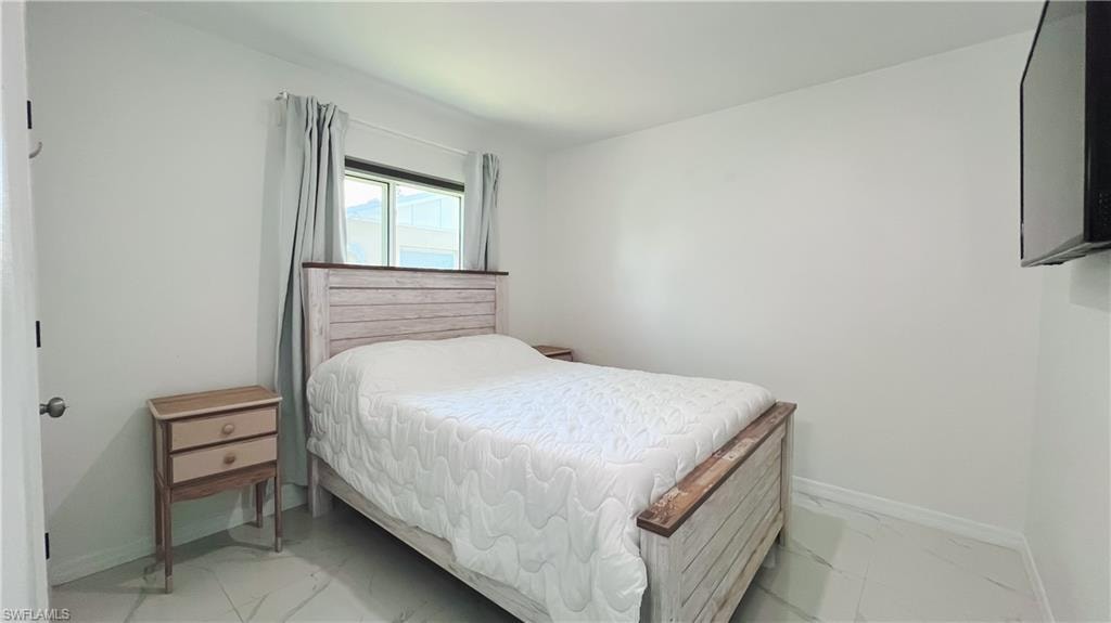 Bedroom with baseboards and light marble finish floors