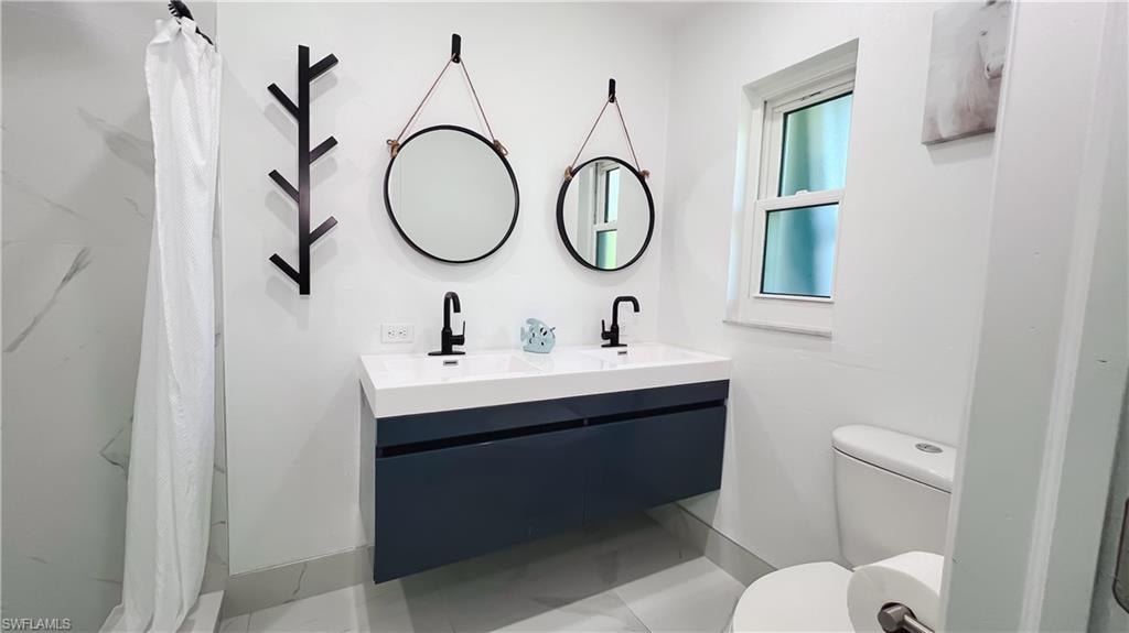 Full bath with double vanity and a shower with shower curtain