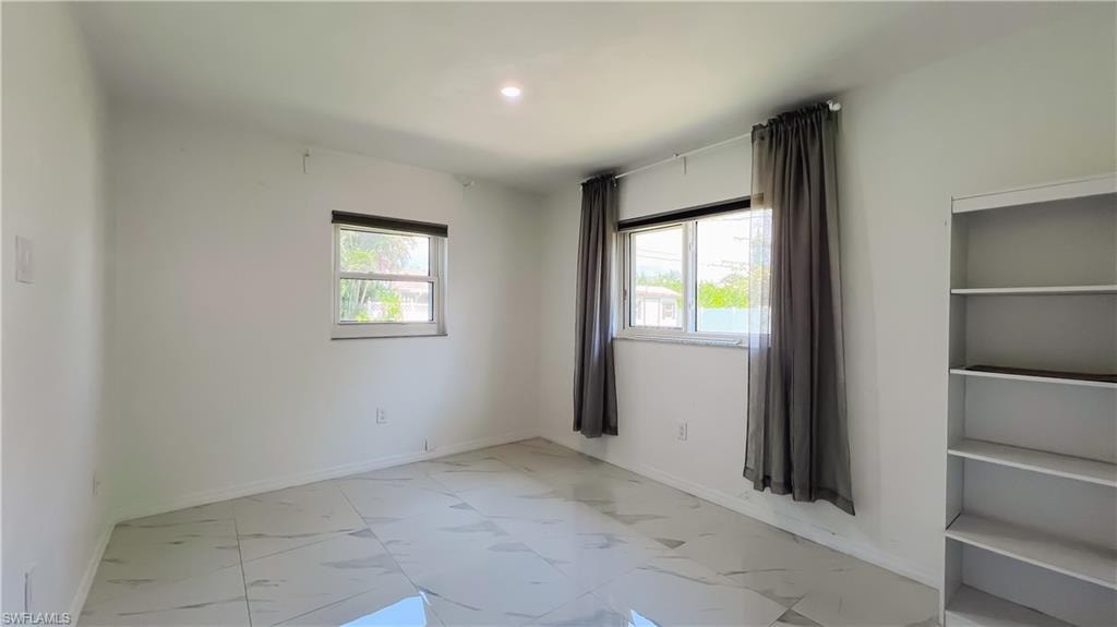 Unfurnished room with light marble finish floors, plenty of natural light, and recessed lighting