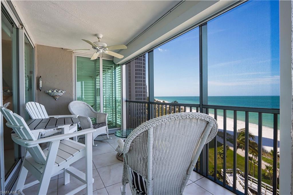 Balcony with a ceiling fan and view of water and beach