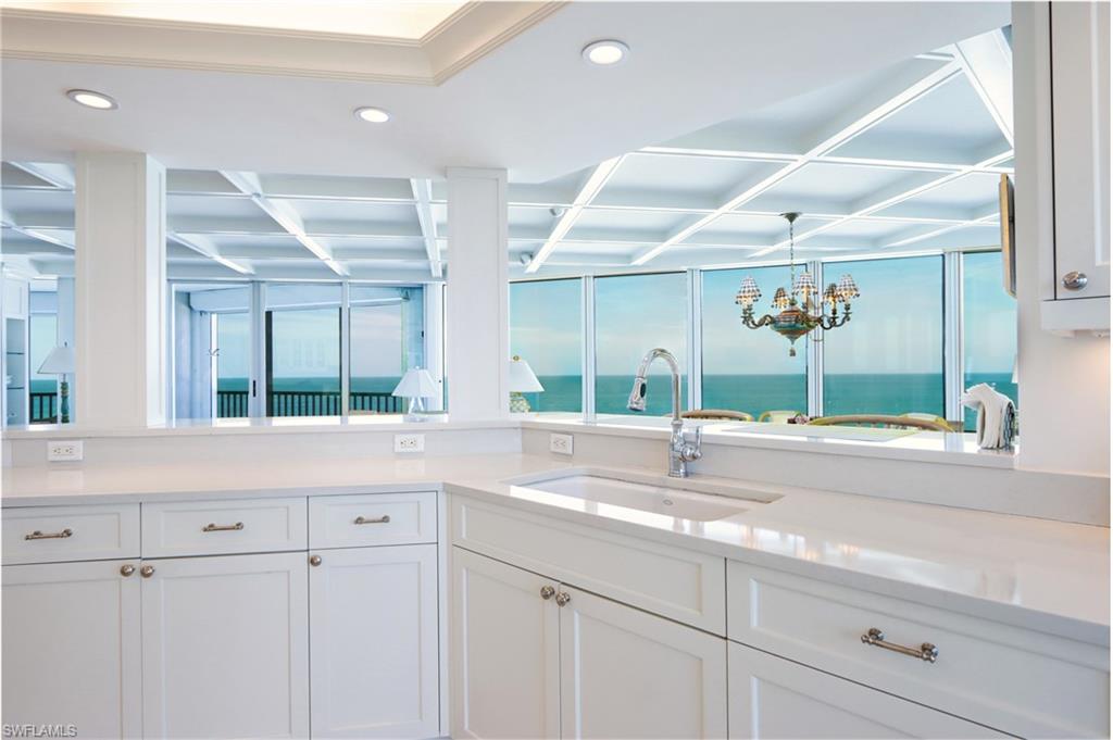 Kitchen with white cabinetry, light stone counters, a chandelier, and a water view