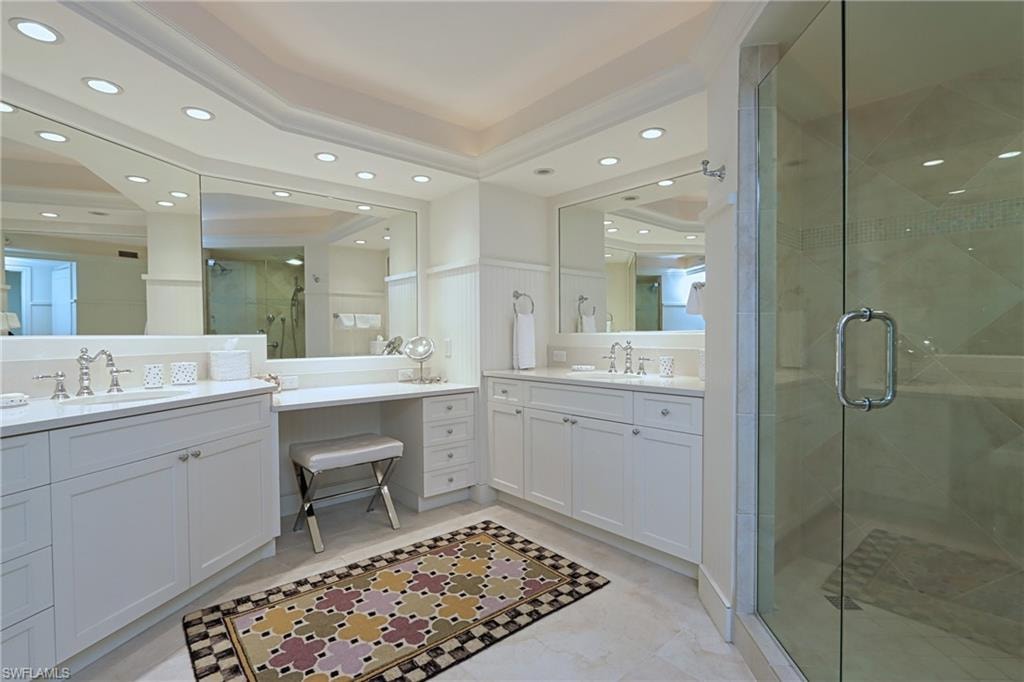 Bathroom featuring a stall shower, recessed lighting, a raised ceiling, and two vanities
