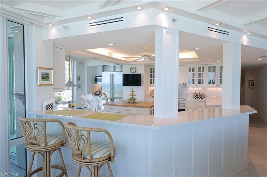 Kitchen with glass fronted cabinets, white cabinets, stainless steel appliances, recessed lighting, and a tray ceiling