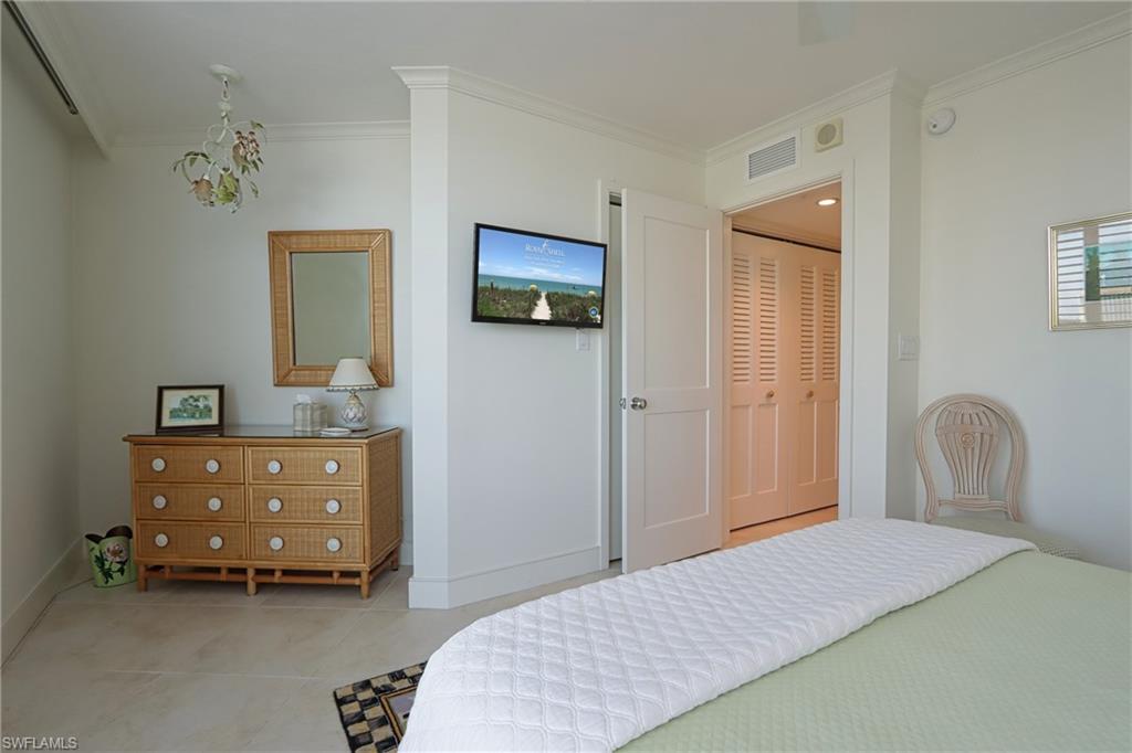 Bedroom featuring light tile patterned flooring, ornamental molding, and a closet