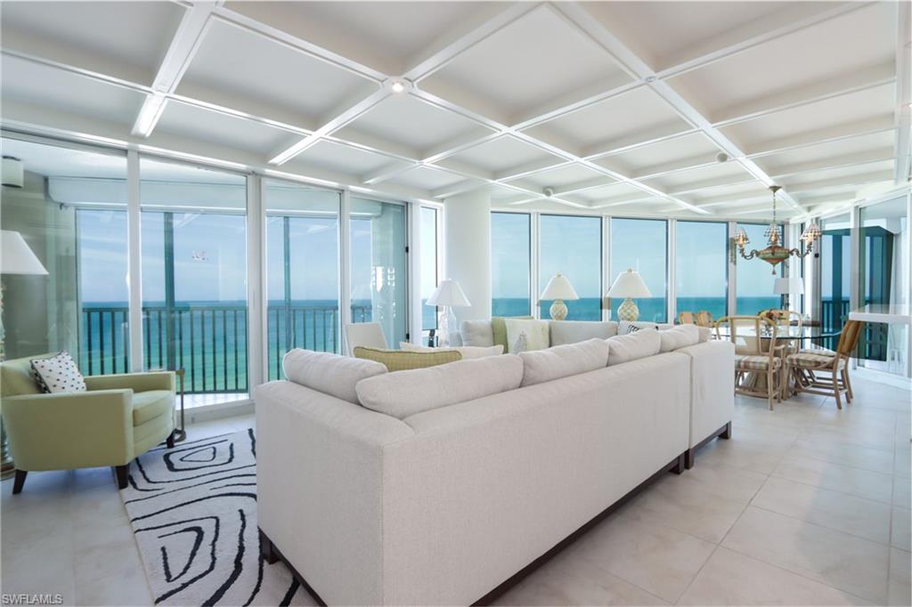 Living area featuring coffered ceiling, expansive windows, a water view, and a chandelier