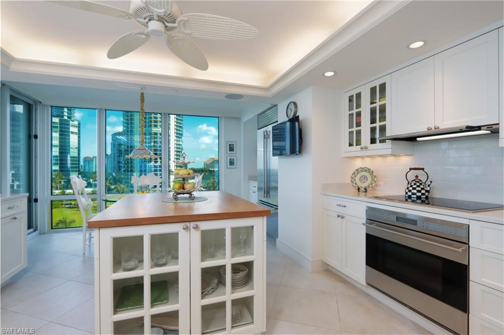 Kitchen featuring glass insert cabinets, stainless steel appliances, white cabinets, a kitchen island, and ceiling fan