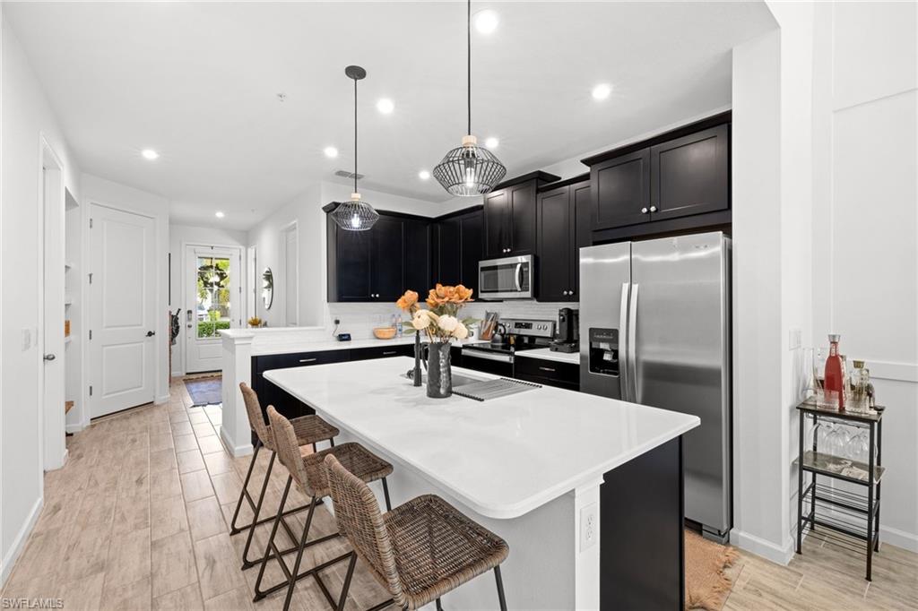 Kitchen featuring dark cabinetry, stainless steel appliances, a center island, and hanging light fixtures