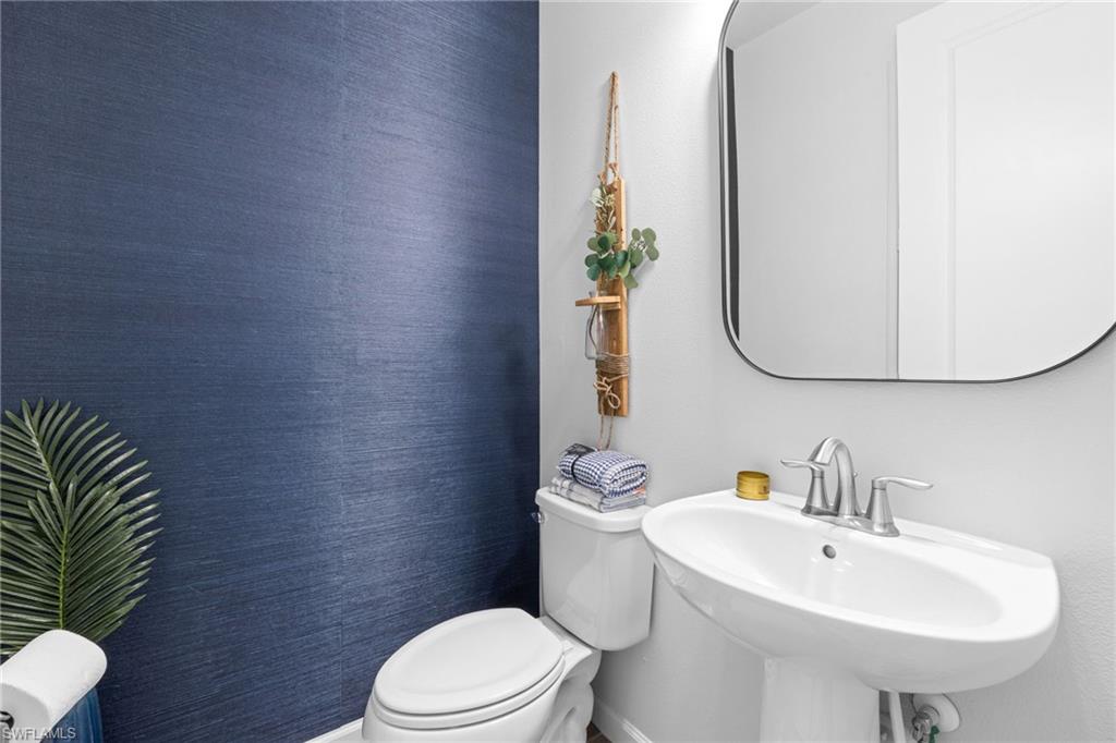 Bathroom with toilet and wallpapered walls