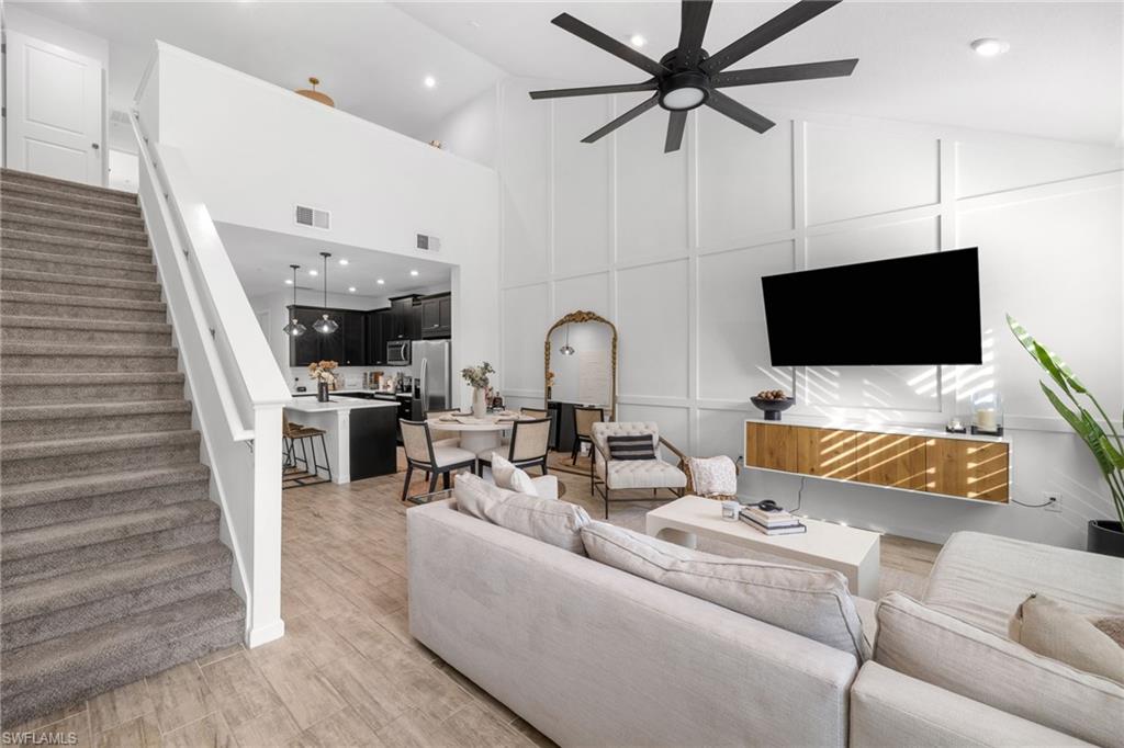 Living area with vaulted ceiling, a decorative wall, ceiling fan, recessed lighting, and light wood finished floors