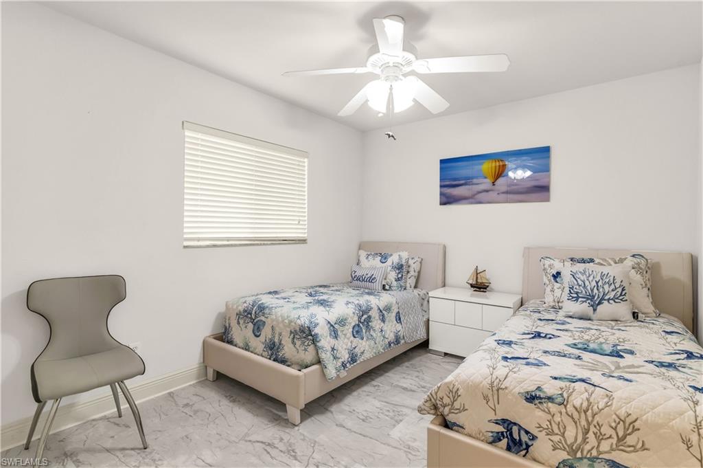 Bedroom with ceiling fan and light marble finish flooring