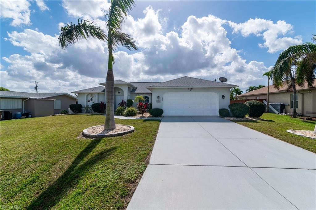 Ranch-style house featuring driveway, a front lawn, an attached garage, and stucco siding
