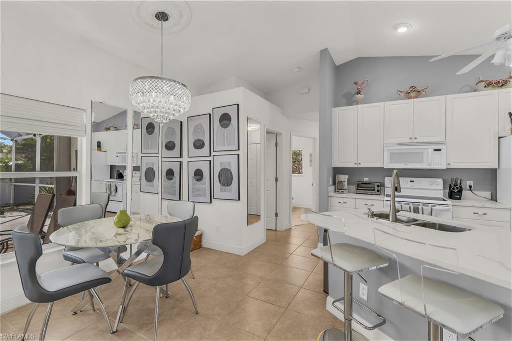 Dining area featuring vaulted ceiling, ceiling fan, a chandelier, and light tile patterned floors