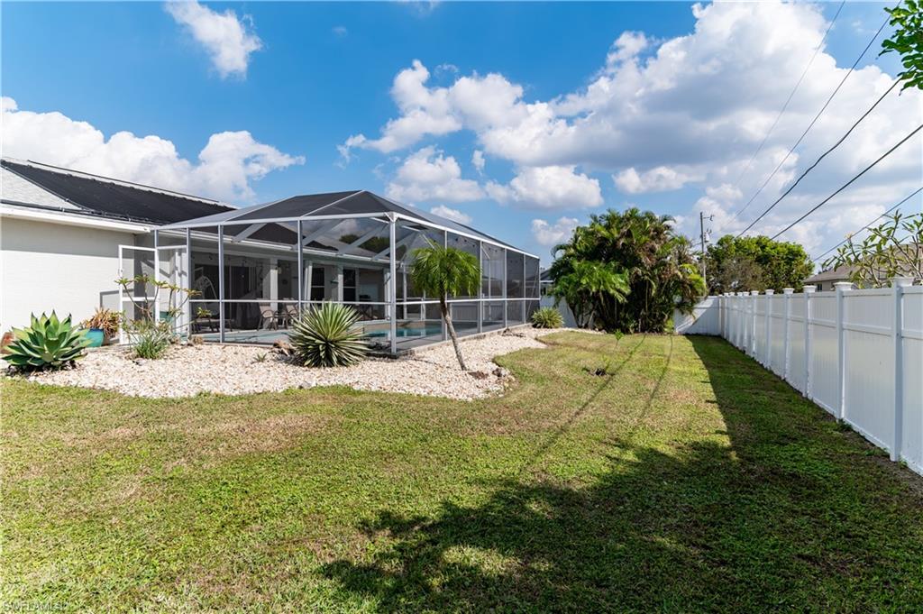 Back of house with a sunroom, a lanai, an outdoor pool, a fenced backyard, and a patio