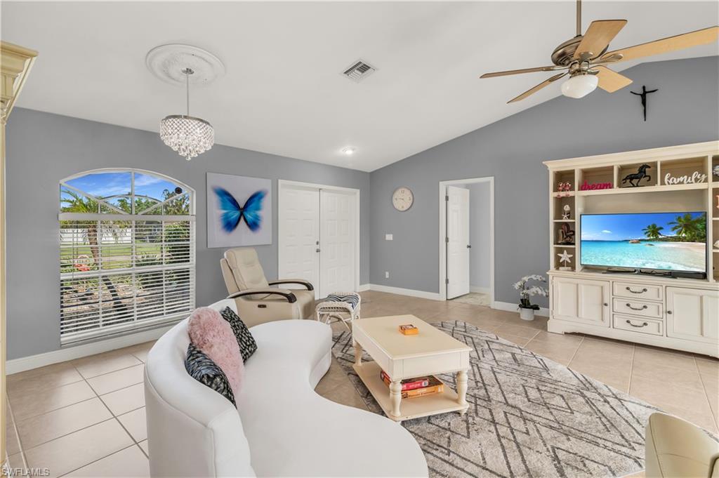 Living room with light tile patterned floors, suspended lighting, ceiling fan, and vaulted ceiling