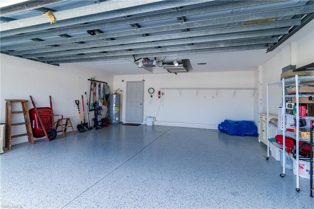 Garage featuring electric water heater and a garage door opener