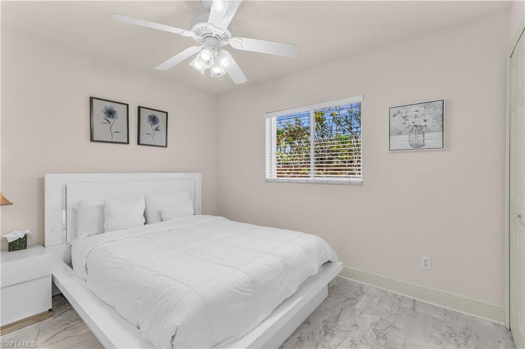 Bedroom with ceiling fan and light marble finish floors