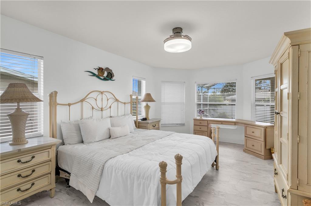Bedroom with light marble finish floors, multiple windows, and a ceiling fan
