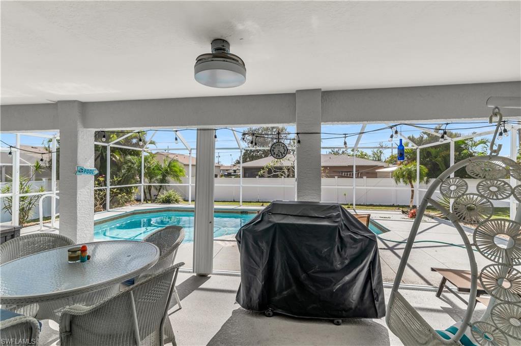 View of swimming pool with glass enclosure, a sunroom, grilling area, patio surround, and outdoor dining space