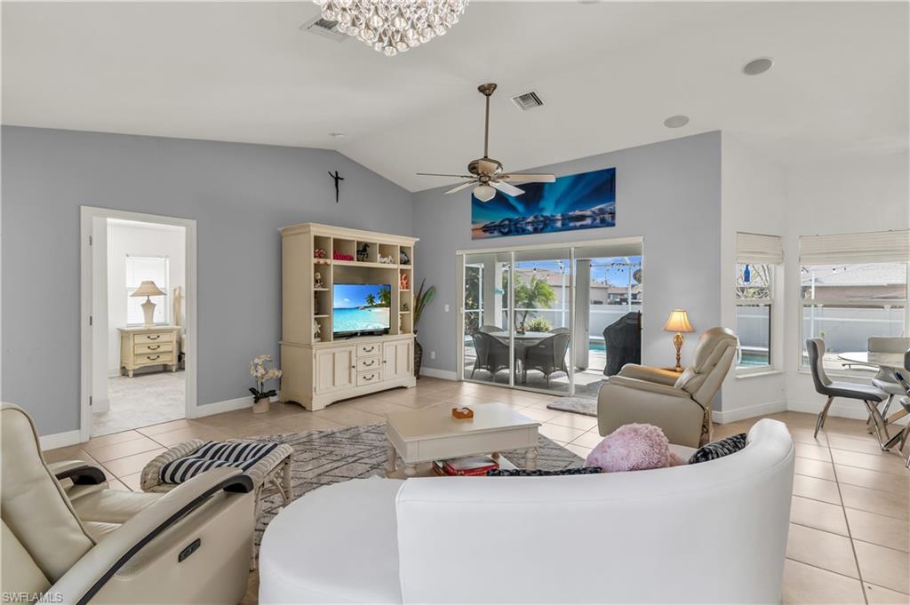 Living area featuring lofted ceiling, light tile patterned floors, and ceiling fan