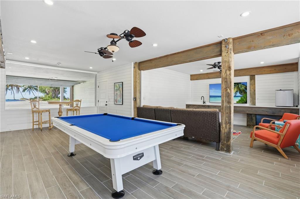 Rec room with wooden walls, a ceiling fan, wood tiled floors, billiards, and recessed lighting - Virtually Edited Image
